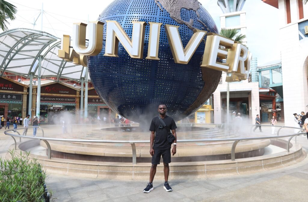 Kojo Enoch standing in front of the iconic Universal Studios globe in Singapore