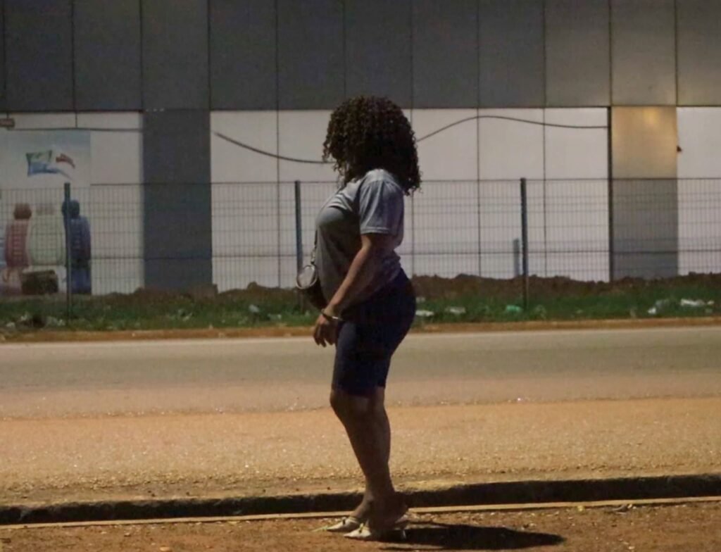 Woman standing alone at night on a roadside in Africa.