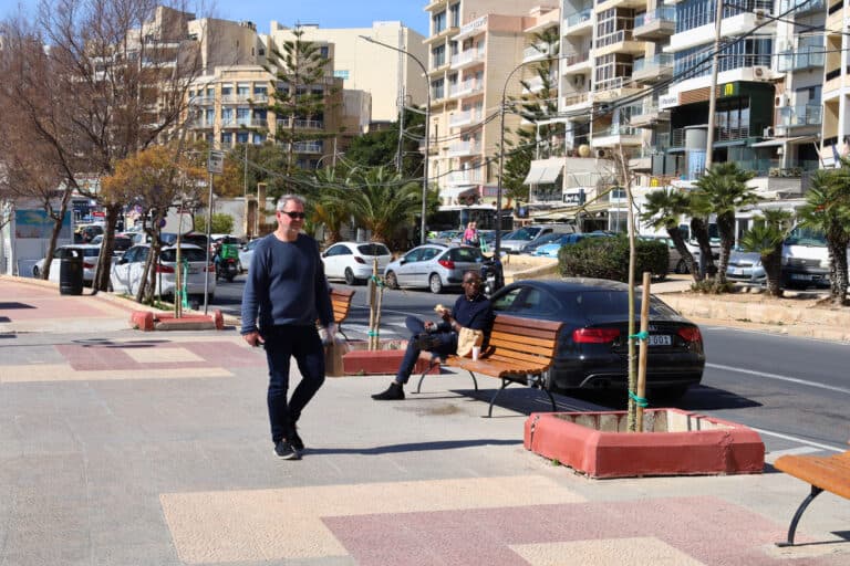 Businessman walking along Sliema’s seaside boardwalk in Malta