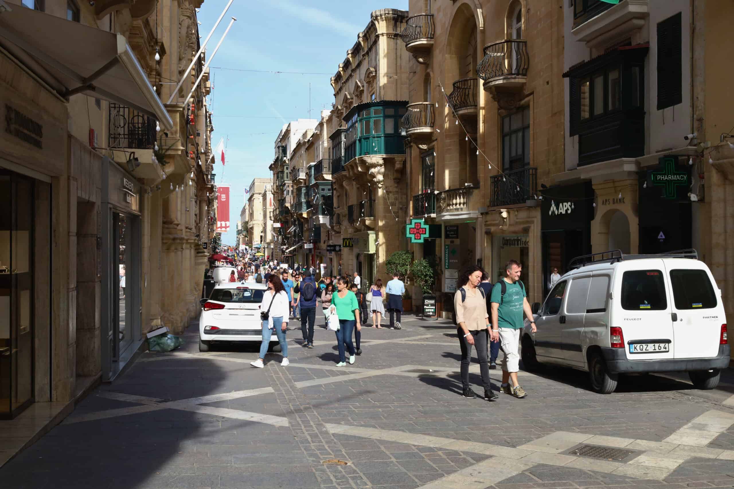 Pedestrians and cars on Valletta’s main road during daytime