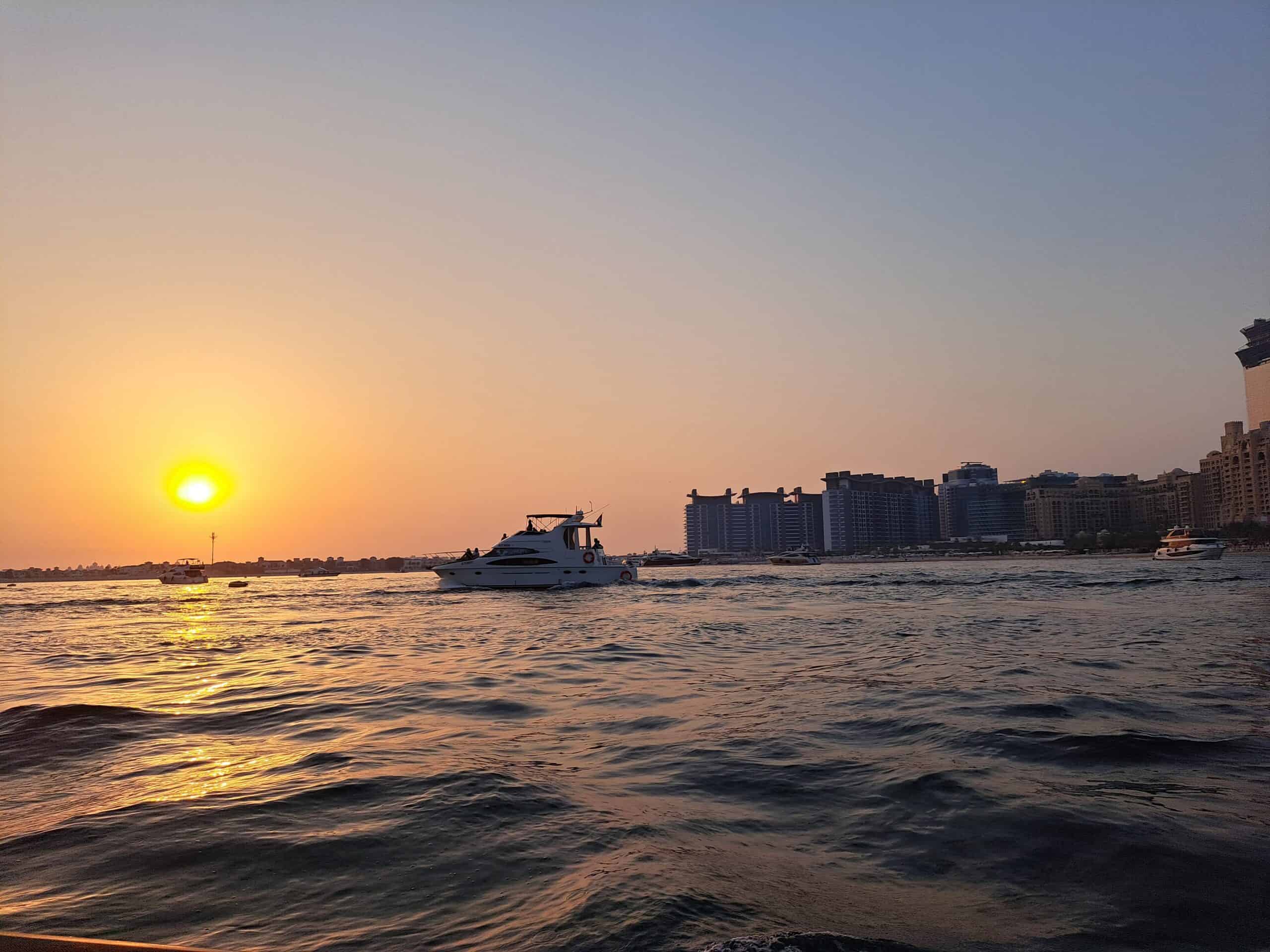 Boats floating during sunset at Dubai Marina with an orange sky