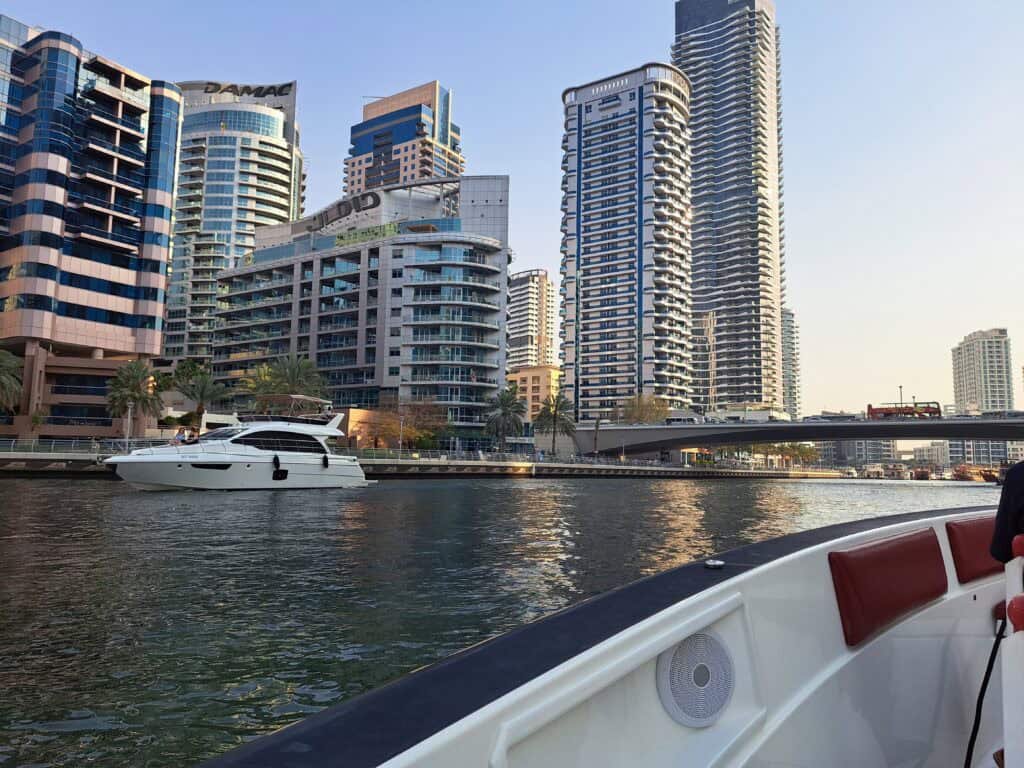 A view of Dubai Marina from a boat with yachts and modern towers along the waterfront