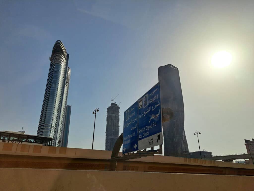 Dubai skyline with road signs and bright sun in the sky