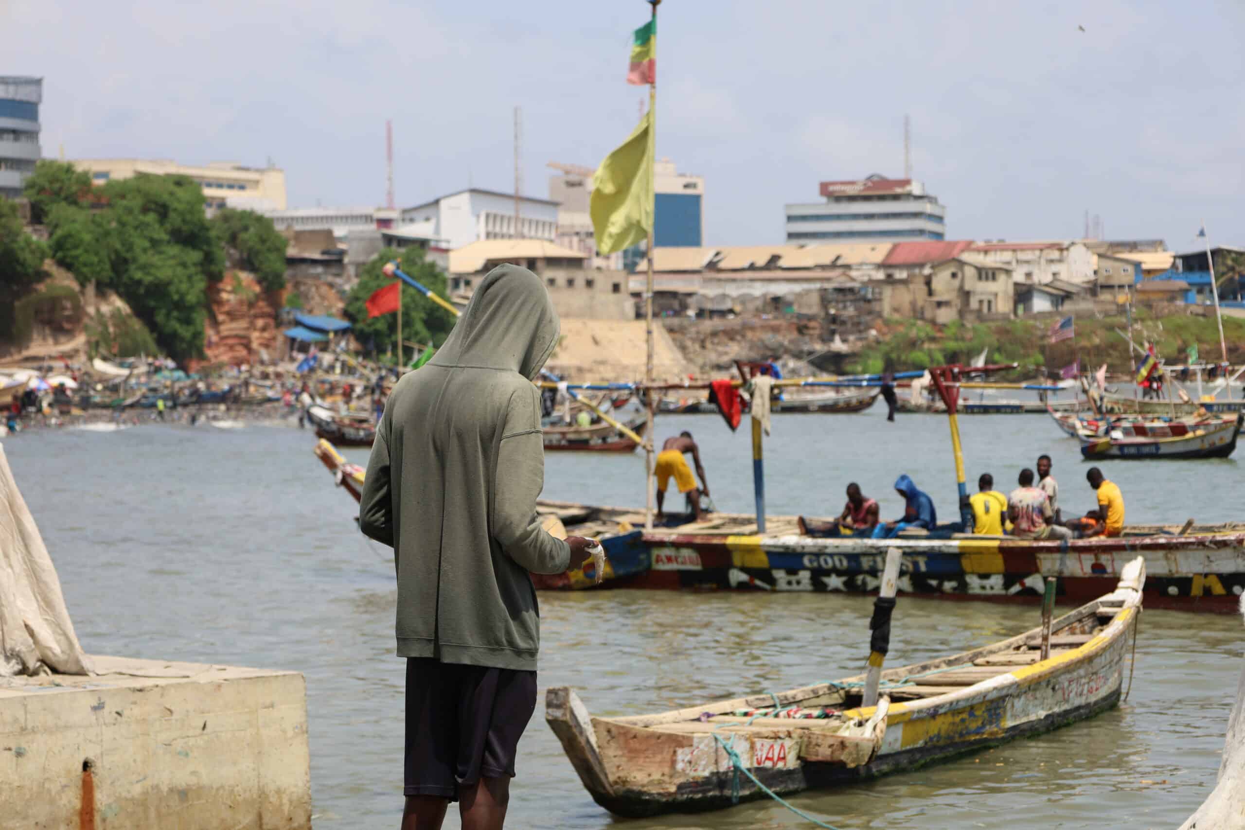 own harbor in Accra, Ghana. Alt Text: Fishermen mending fishing nets at Jamestown.
