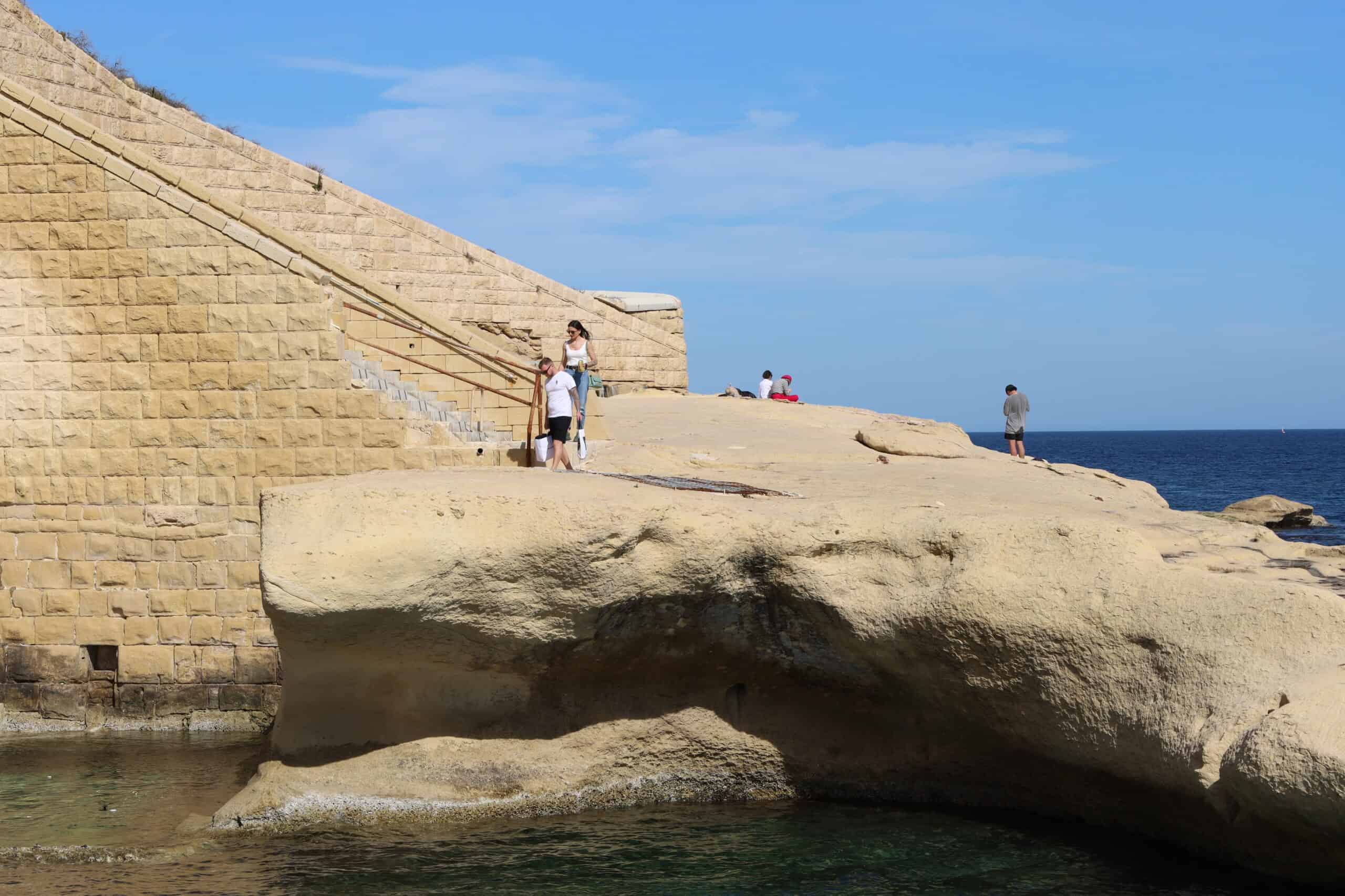 Woman walking along a cliffside trail in Malta