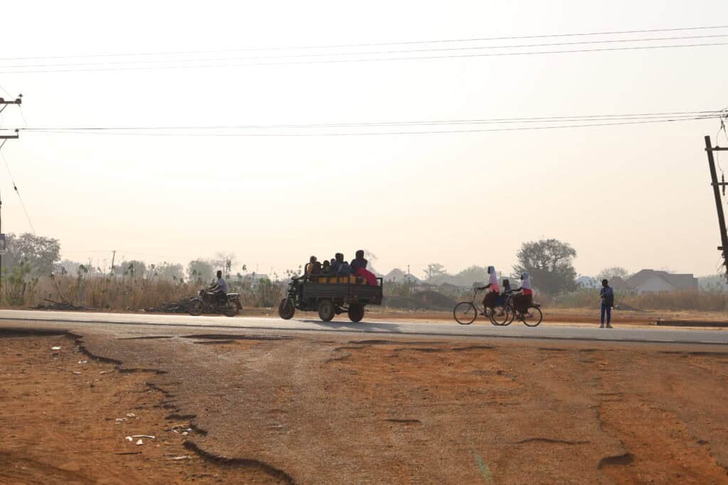 People crossing red dirt road in Tamale, Ghana.