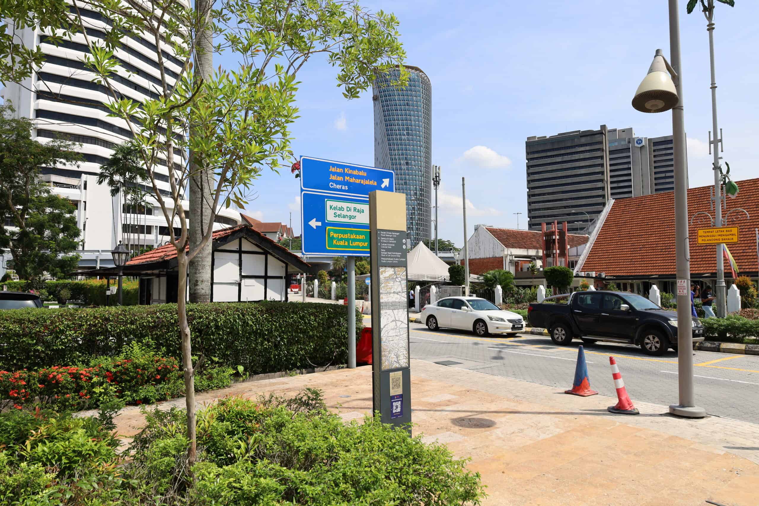 Urban streetscape in Kuala Lumpur with signposts and small shops