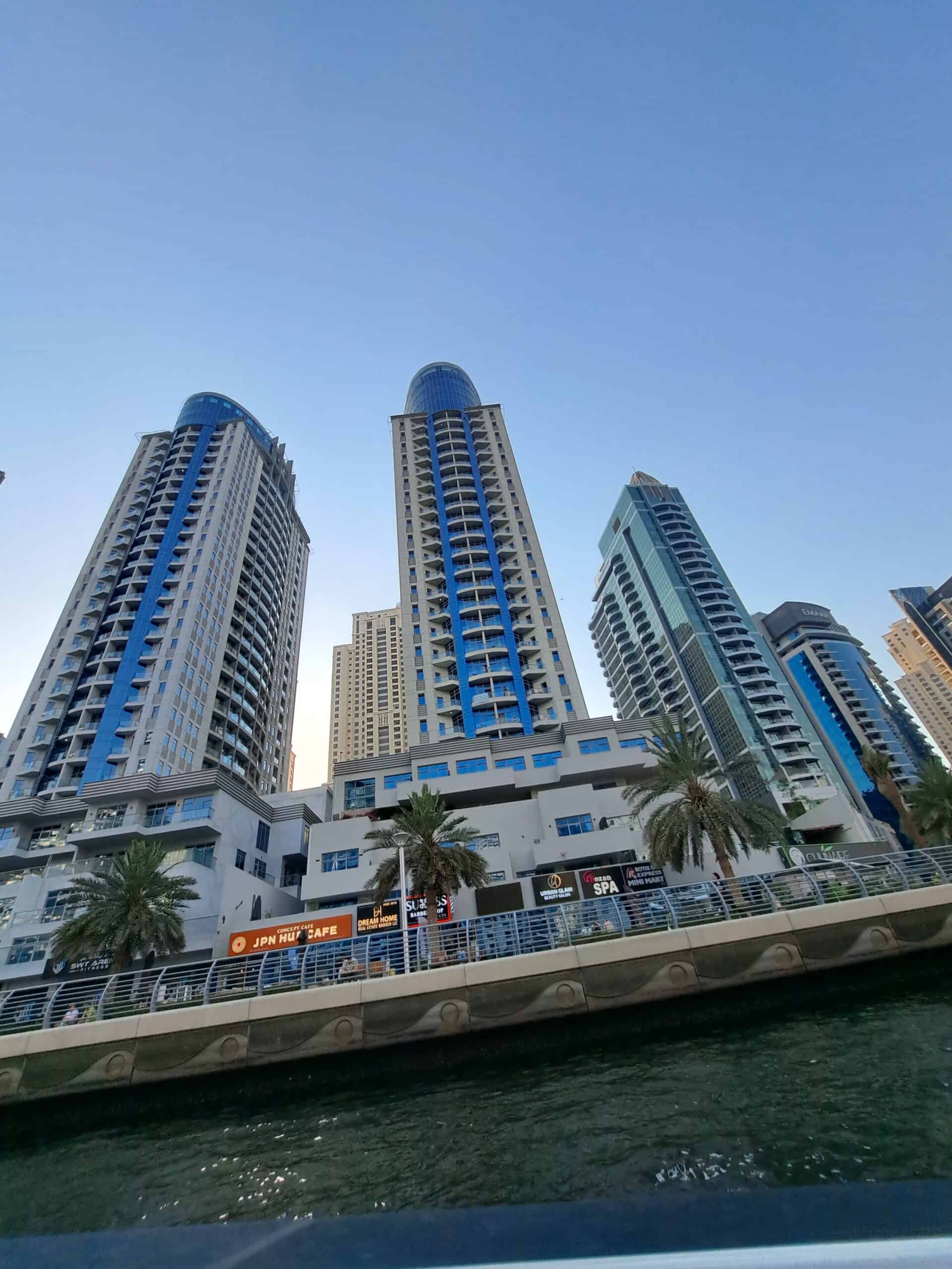 Upward view of several tall towers in Dubai Marina with a clear blue sky