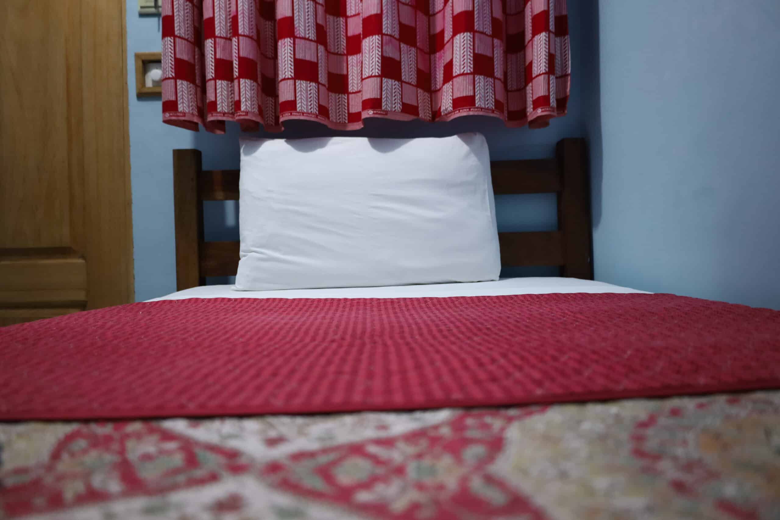 Pillow and curtains inside Sharpnet Guest House budget room in Accra.