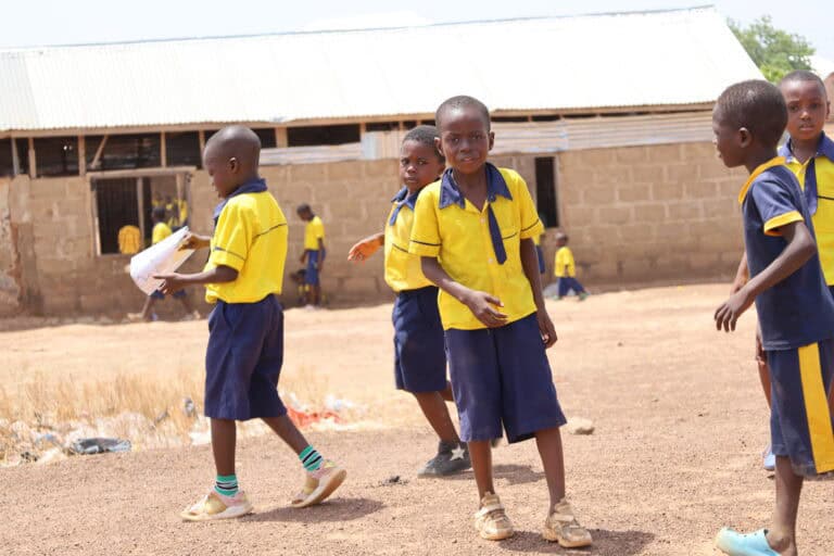 Schoolboys in uniform playing outside rural school.