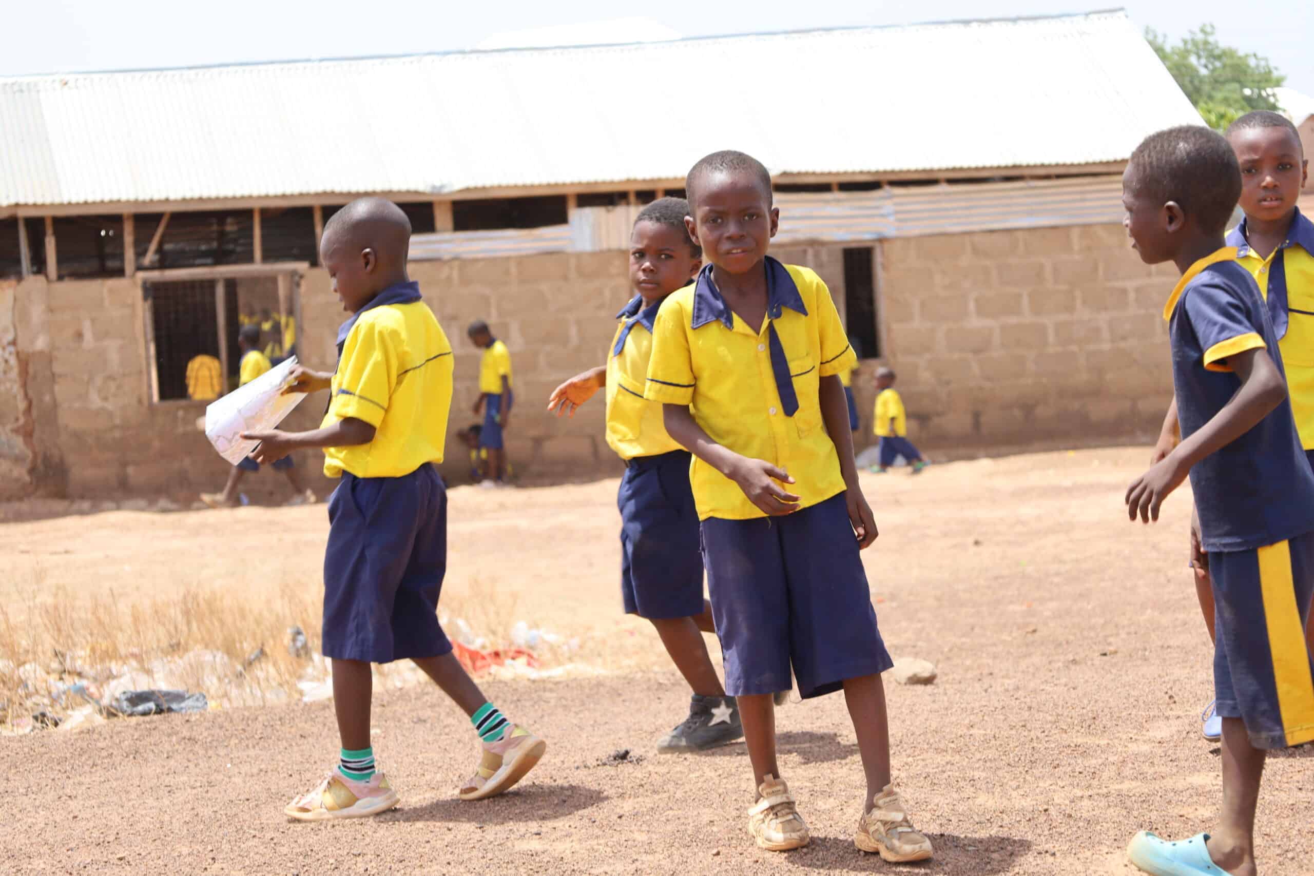 Schoolboys in uniform playing outside rural school.