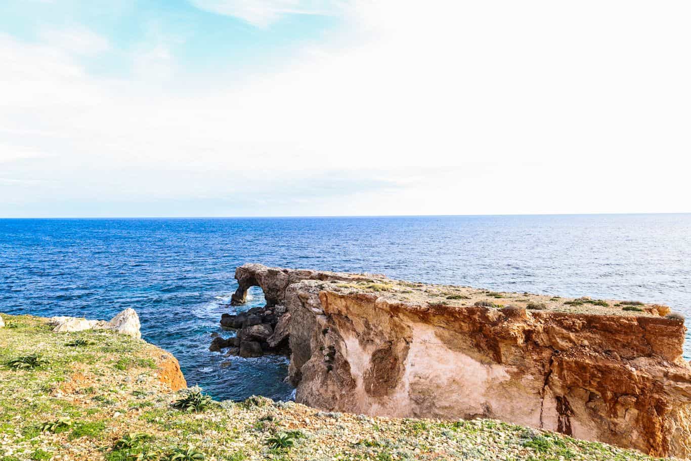 Natural stone arch formation on the rugged coastline of Qrendi, Malta.