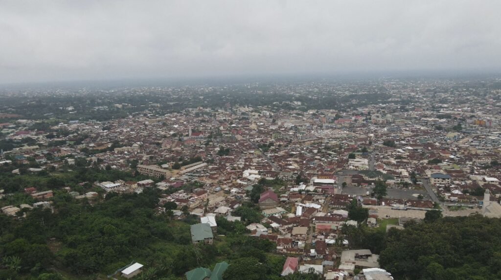 Aerial view of a densely packed city in Ghana surrounded by greenery.