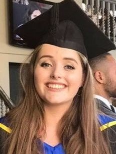 Young woman in graduation gown smiling on her graduation day