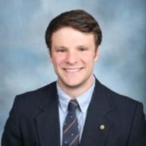 Portrait of Otto Warmbier in a dark suit with a light blue background