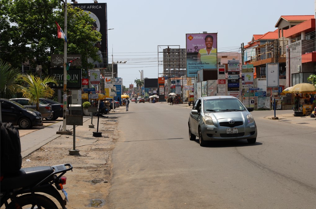 A mix of modern vehicles passing through a busy street in central Accra