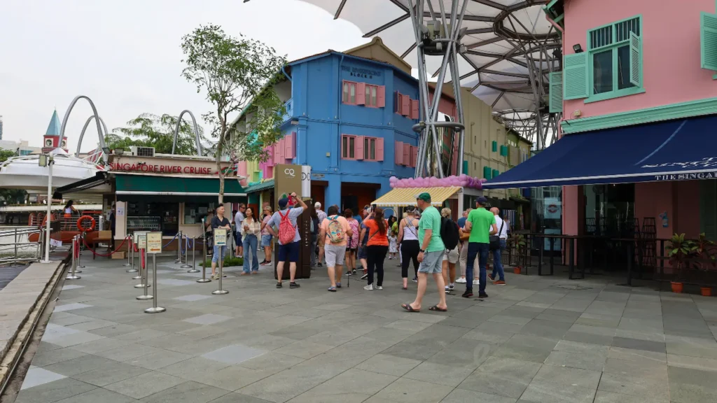 Tourists walking past colorful heritage shophouses in Clarke Quay, Singapore