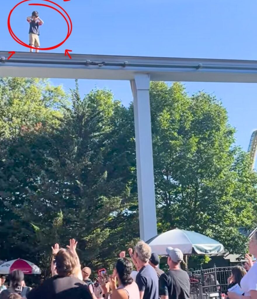 A confused boy covers his ears while standing on top of the Hersheypark monorail track as a crowd yells from below.