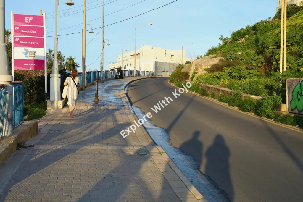 People walking along a street during sunrise in Malta.