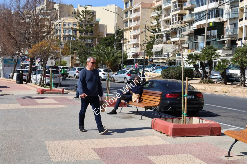 Promenade with people walking near modern buildings in Sliema, Malta.