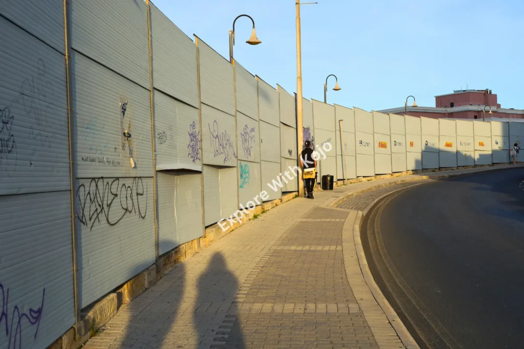 Pedestrian walkway beside graffiti-covered&nbsp;fence&nbsp;in&nbsp;Malta.