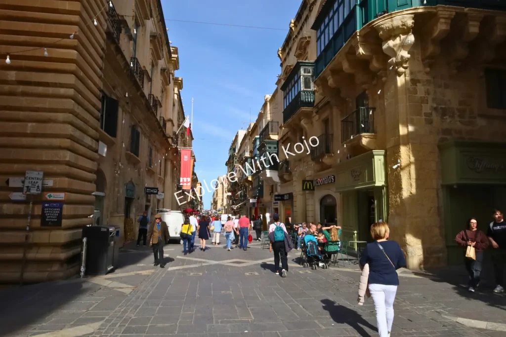 Pedestrians walking on a street in Valletta, Malta.