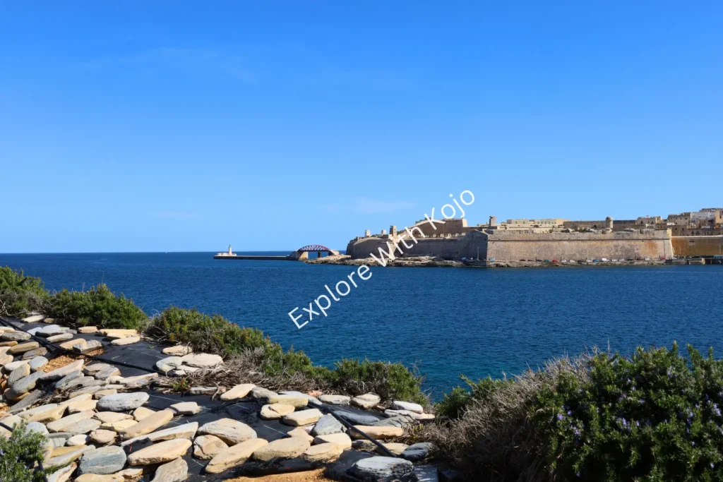 Rocky coastal landscape with distant fortifications in Malta.