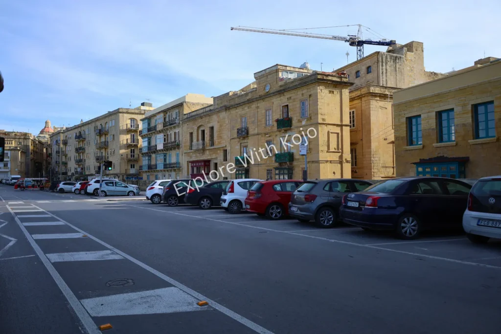 Limestone buildings and parked cars along a Maltese street.