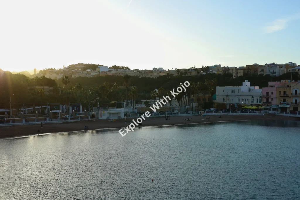 Sunrise over Mellieha Bay with calm waterfront in Malta.