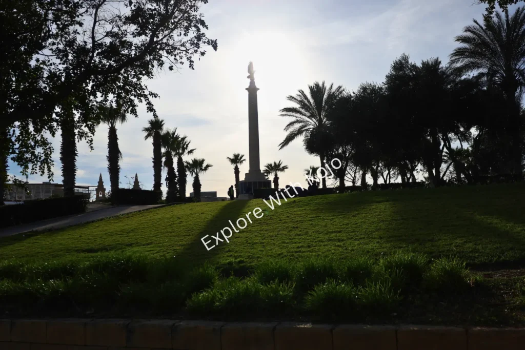 Monument silhouette among palm trees in park, Malta.