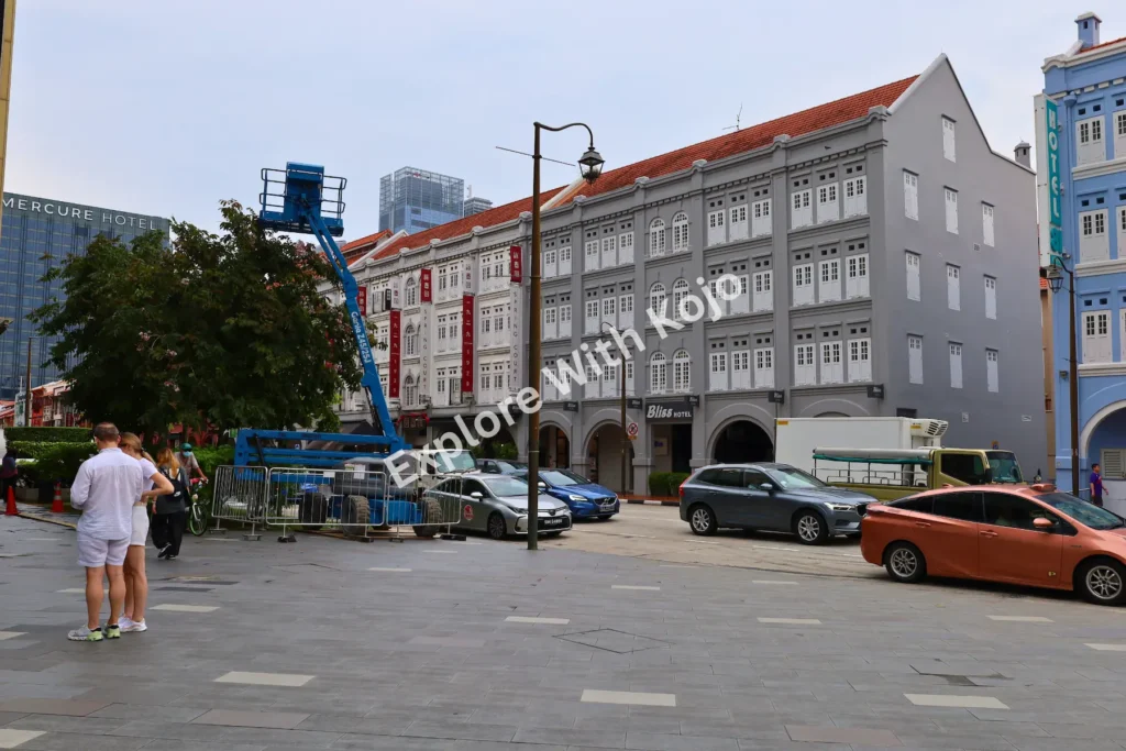 Bustling Chinatown street in Singapore with cars and pedestrians.