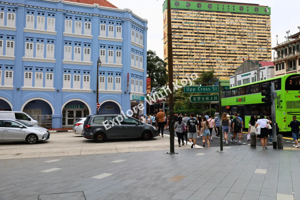 People crossing New Bridge Road with colorful shophouses in Chinatown Singapore.
