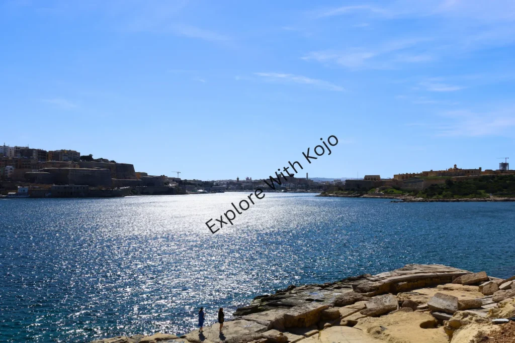 Sunlit bay rocky shoreline Malta.