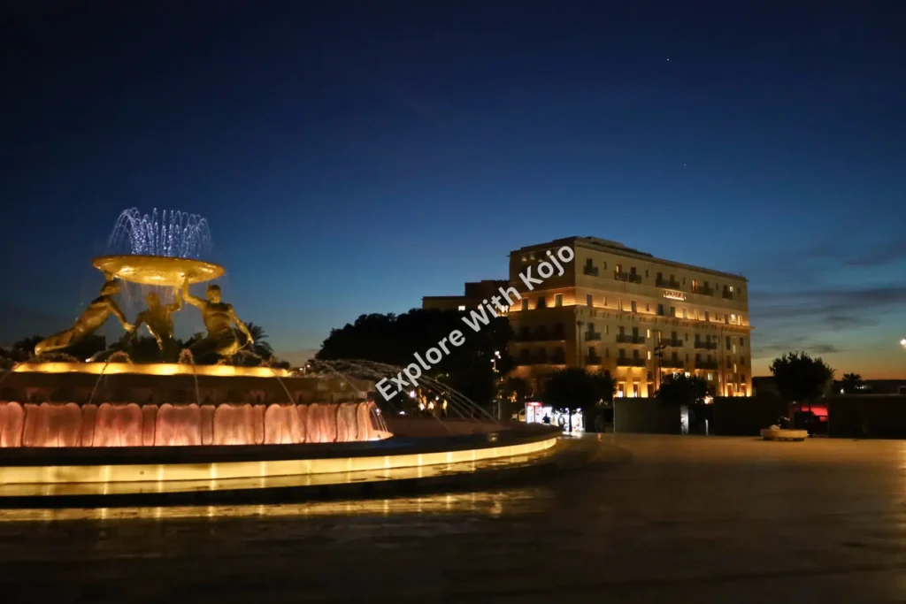 Triton Fountain in Valletta Malta lit up at night.