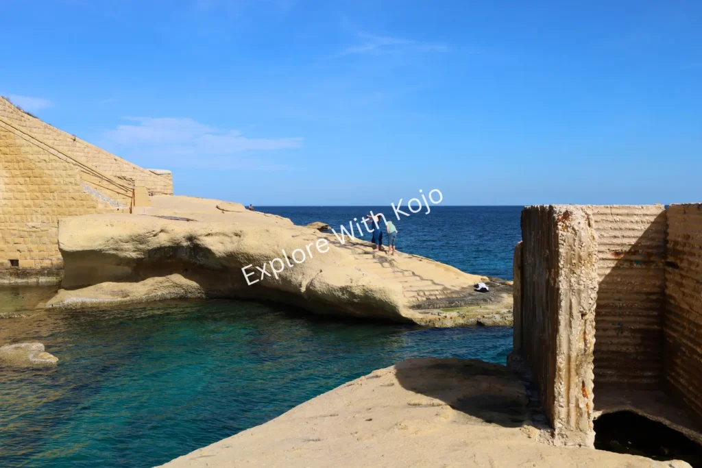 Turquoise cove in Malta with weathered stone formations.