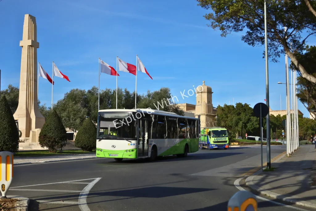War Memorial in Valletta Malta with flags and buses.
