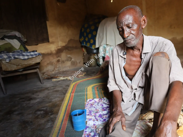 Elderly poor African man sitting inside a mud hut