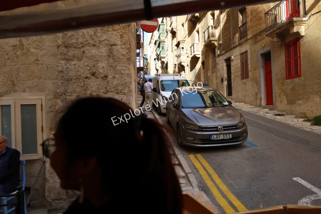 Woman walking in Valletta street with stone&nbsp;buildings.