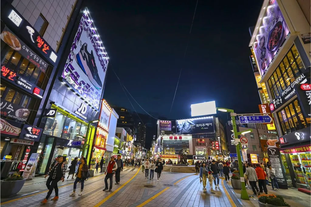 Busy nightlife street in Busan with neon lights.