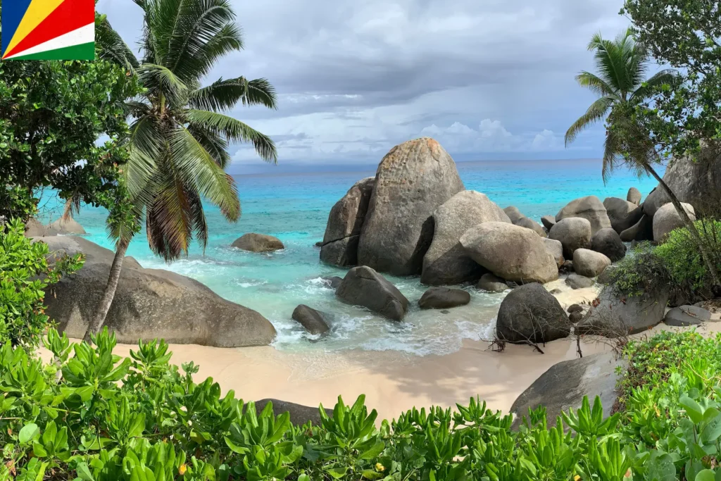 Palm trees and granite boulders by a tropical beach in Seychelles.