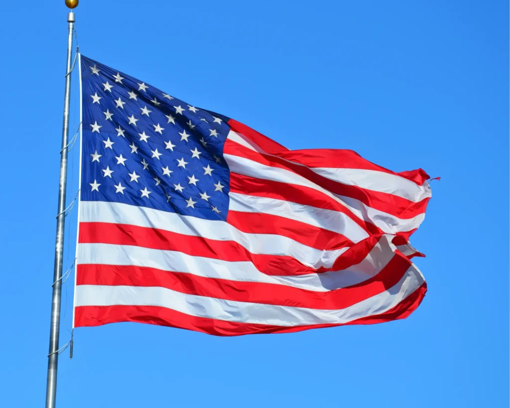 American flag waving on a pole against a clear blue sky.