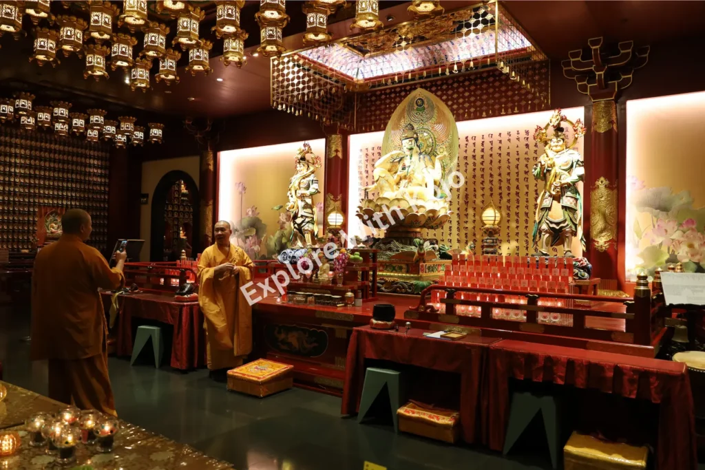 Large Buddha statue surrounded by hanging lanterns in the prayer hall.