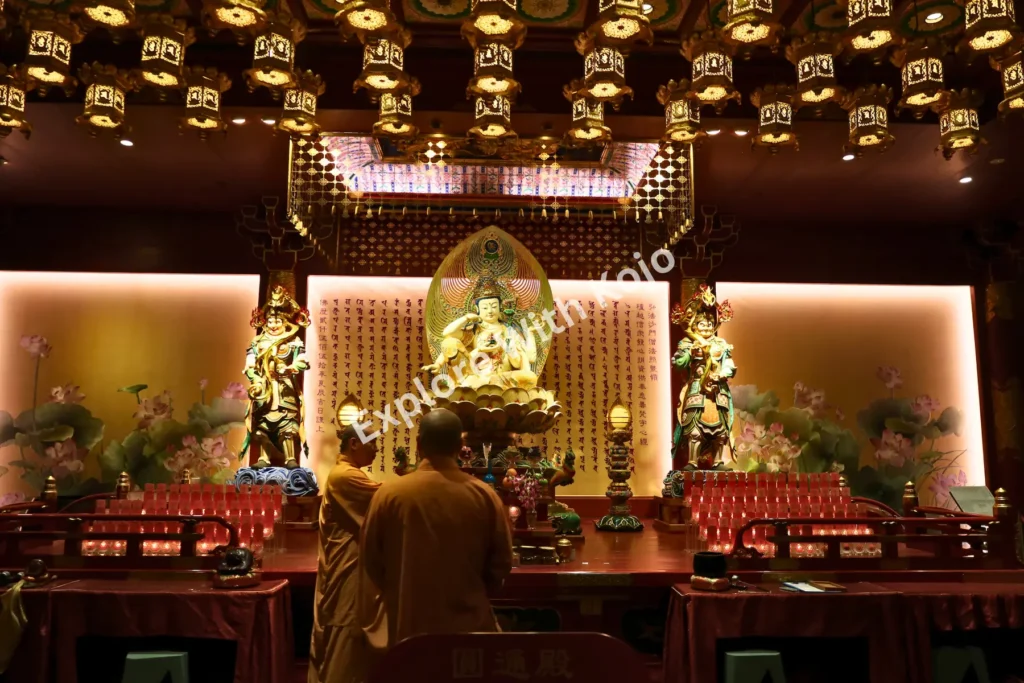 Monks standing in front of a large golden Buddha inside the temple’s prayer hall.