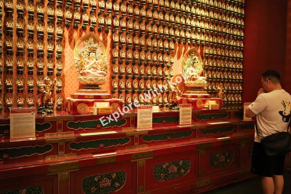 Worshipper making offerings at golden altar in Buddha Tooth Relic Temple.