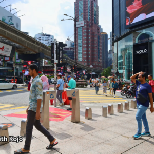 Pedestrians crossing the street at Bukit Bintang with tall billboards in the background