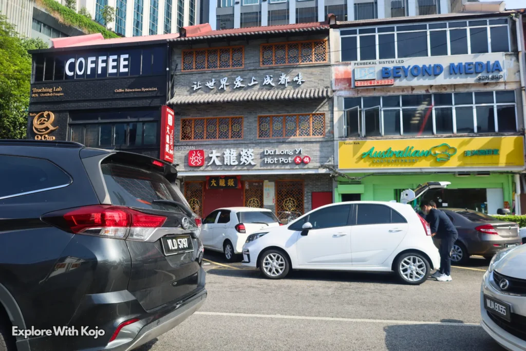 Classic Kuala Lumpur shoplots with coffee cafés, parked cars and pedestrians near Bukit Bintang.