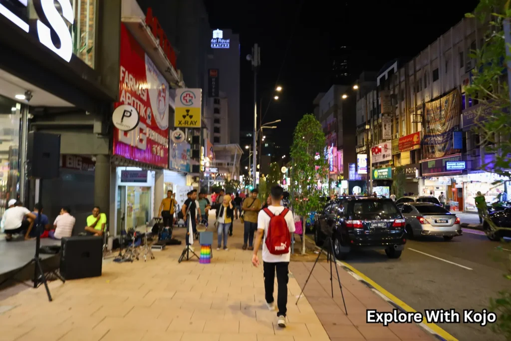 People walking along Bukit Bintang street under city lights at night