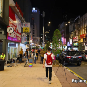 People walking along Bukit Bintang street under city lights at night
