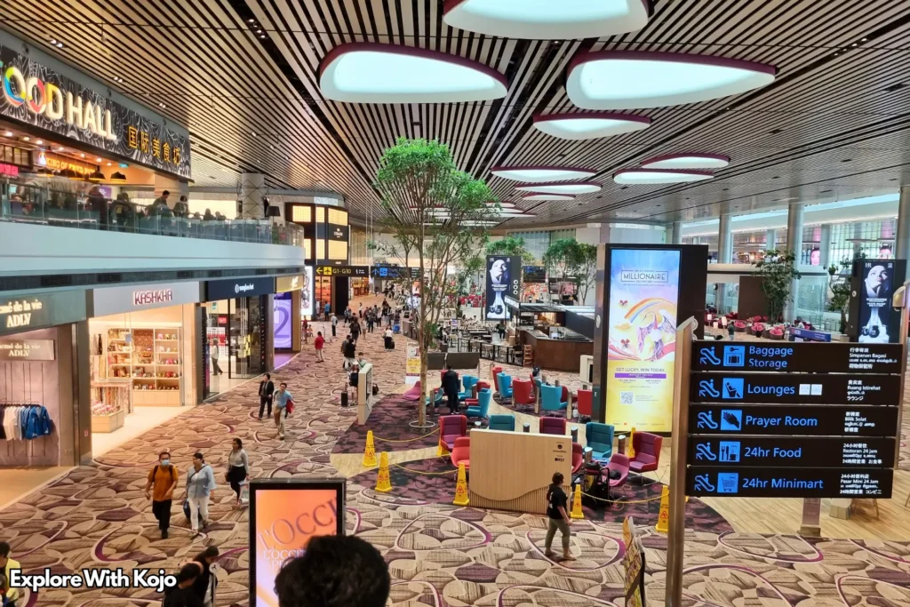 Interior view of Changi Airport Terminal 2 departure hall with shops, food court, and passengers.