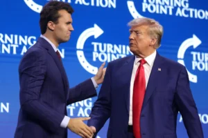 Charlie Kirk shaking hands with Donald Trump during a Turning Point Action event